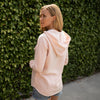 Woman poses in a pastel pink pullover hoodie.