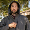 Close up of man zipping up tech jacket with the hood on.
