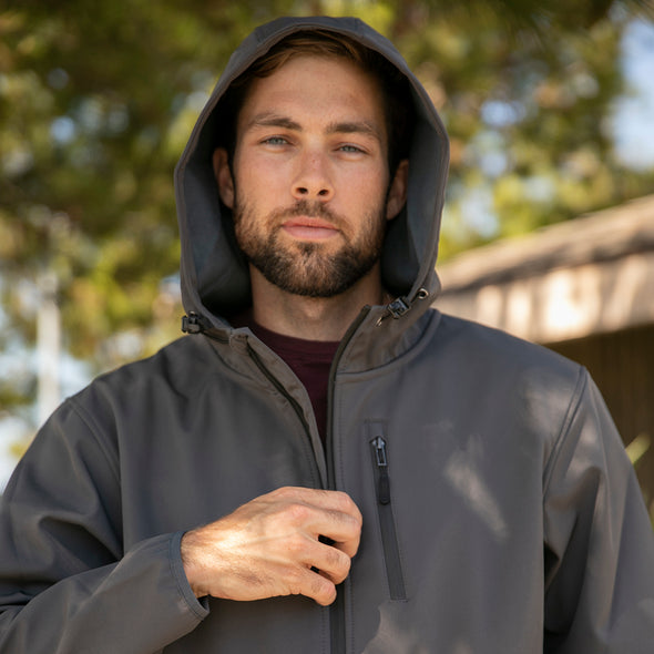Close up of man zipping up tech jacket with the hood on.