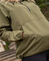 Close up of an army green windbreaker, highlighting its elastic cuffs and kangaroo pocket.