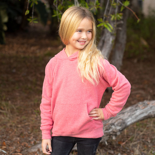 Girl poses in a pomegranate pink pullover hoodie and black jeans.