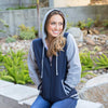 Woman poses in varsity style hoodie.