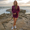Woman poses on the beach in a burgundy sweater dress.