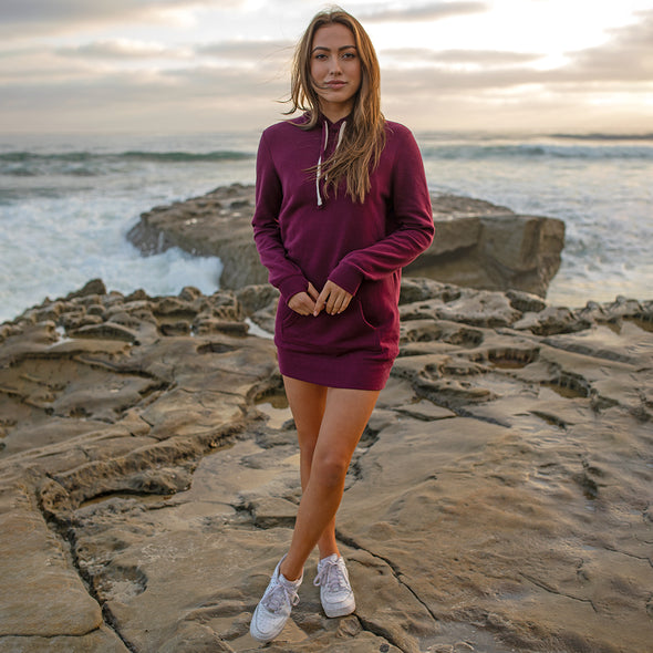 Woman poses on the beach in a burgundy sweater dress.