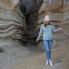Woman poses in a canyon while wearing a pastel green zip-up hoodie.