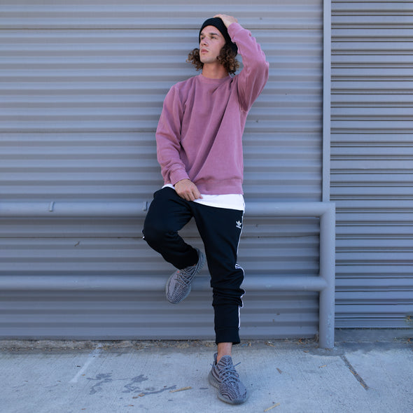 Man poses in a pastel maroon crew neck sweatshirt.