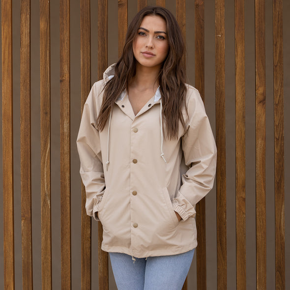 Woman poses in a khaki hooded coach's jacket.